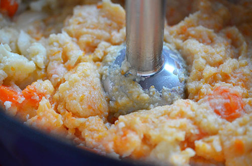 Blending the vegetables for Roasted Garlic Autumn Root Vegetable Mash with an immersion blender.