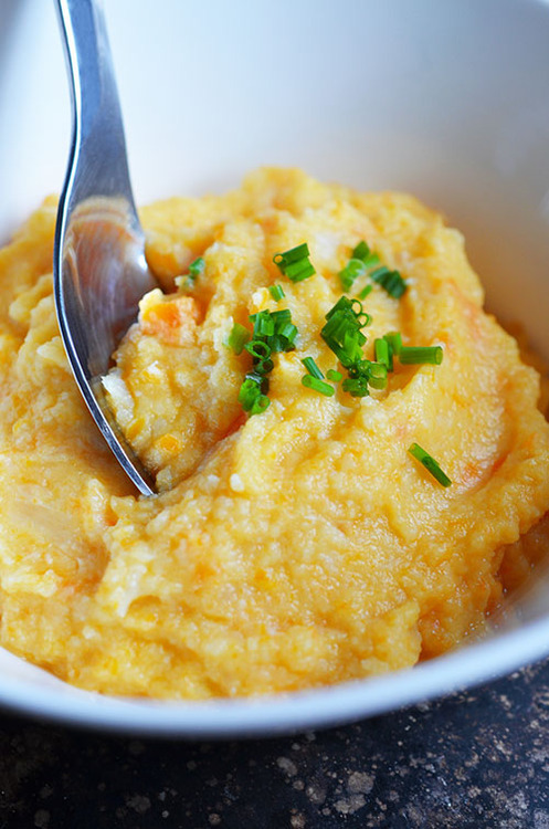 A bowl of Roasted Garlic Autumn Root Vegetable Mash with with a spoon and topped with chives.