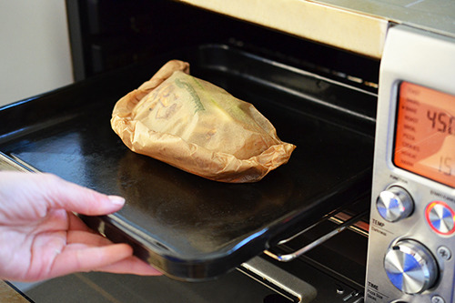 The Fish en Papillote with Citrus, Ginger, & Shiitake is placed in a toaster oven to cook.