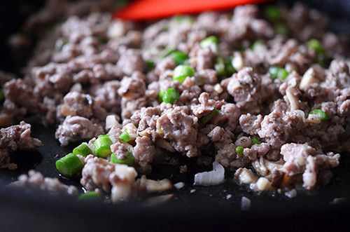 A closeup shot of the cast iron skillet filled the cooked pork, asparagus, shallots, and mushrooms.