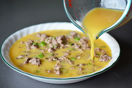 Whisked eggs are poured into the plate containing the custard filling.