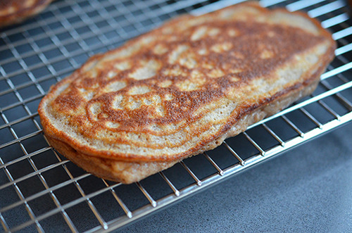 A paleo pancake is resting on a wire rack on a counter.