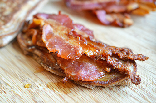 An open-faced Bacon Pancake Sandwich on a wooden cutting board.