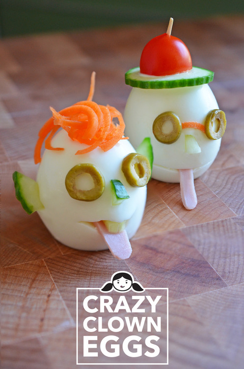 Two hard boiled eggs with faces on them from cut up vegetables.