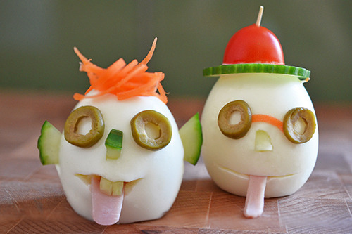 Two crazy clown eggs sitting on a wood cutting board.