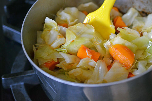A pot of paleo Atkilt Ethiopian Vegetable Stew is being stirred by a yellow spatula.