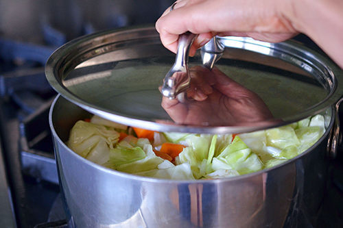 Someone placing a lid on a pot.
