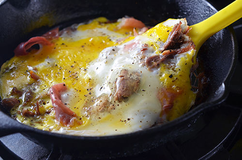 A yellow spatula is lifting Pig In A Skillet to flip it over to finish cooking on the other side.