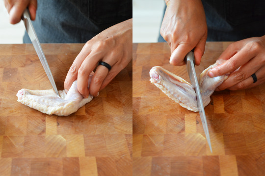 Someone cutting a chicken wing at the joint to separate them.