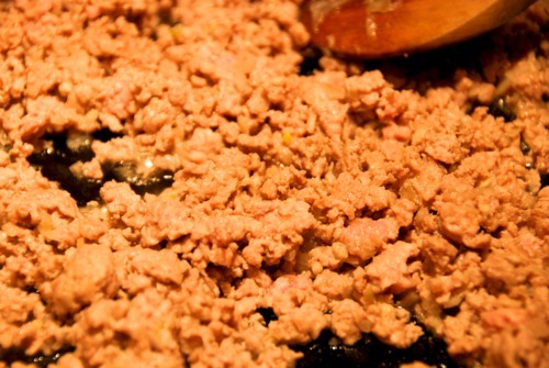 Ground pork frying in a cast iron skillet for the paleo pork and spinach stuffed kabocha squash recipe.