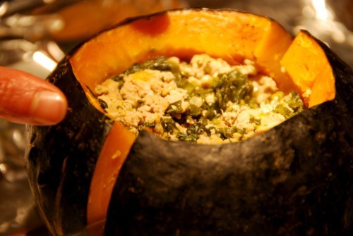 A pork and spinach stuffed kabocha squash is cut in half.