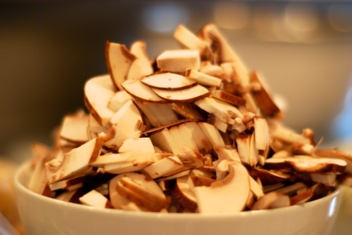 A bowl piled high with thinly sliced cremini mushrooms.