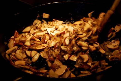Someone frying a mix of mushrooms and onions for muffin frittatas.