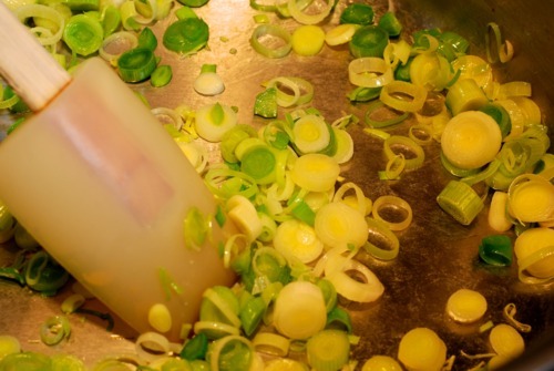 Someone is sautéing green onions in a pan.