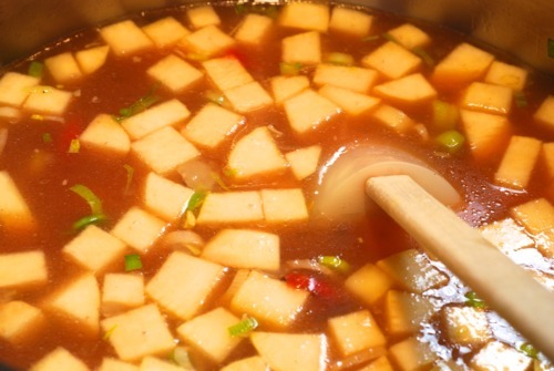 Bone broth is poured into the pan that is making garbage soup.
