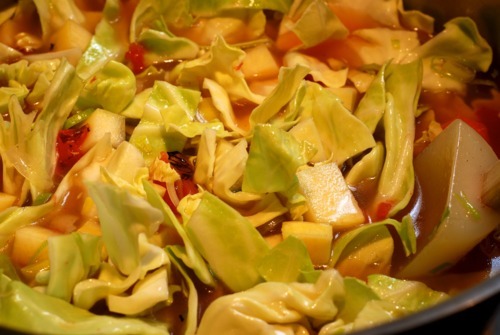 Raw green cabbage is placed into a pot for the garbage soup.