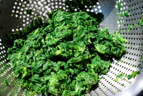 Defrosted frozen spinach in a colander with the water pressed out.