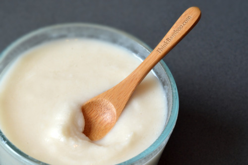 Coconut butter in a glass jar with a small bamboo spoon sticking out of it.