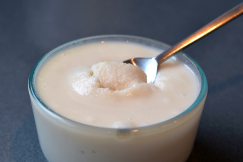 Coconut butter in a small glass jar with a metal spoon sticking out of it.