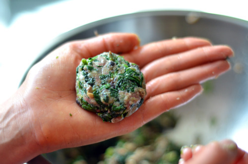 A mini burger formed onto the palm of someone's hand.