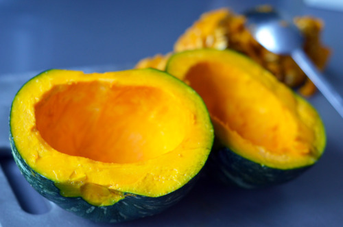 Two halves of a kabocha squash have the seeds removed with a spoon. 
