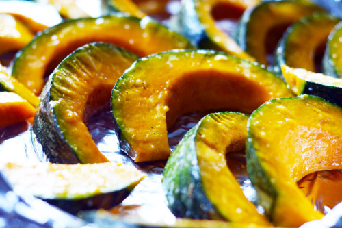 The seasoned kabocha squash wedges are placed on a baking sheet in a single layer. 