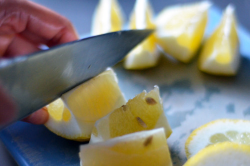 Someone slicing up lemons into wedges.