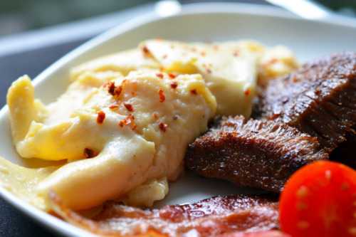 Sous vide scrambled eggs on a plate with bacon.