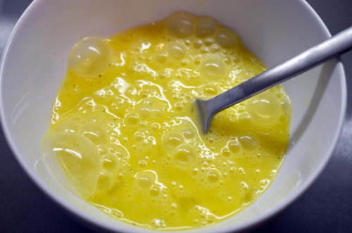 Eggs scrambled in a bowl with a fork inside the bowl.