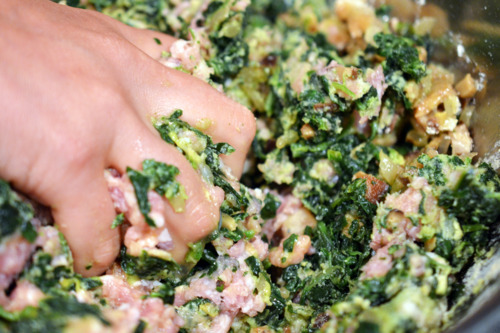 Someone using their hand to mix the ingredients for the pork sliders in a bowl.