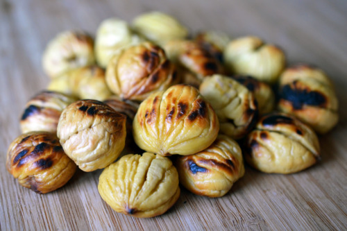 A pile of roasted chestnuts on a cutting board.