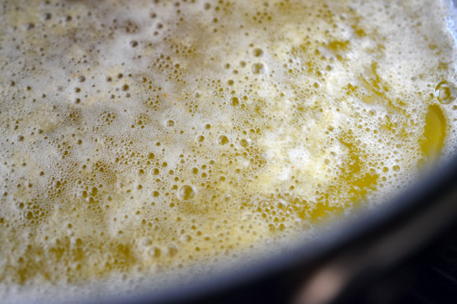 Milk solids starting to form in a saucepan filled with heated up butter.