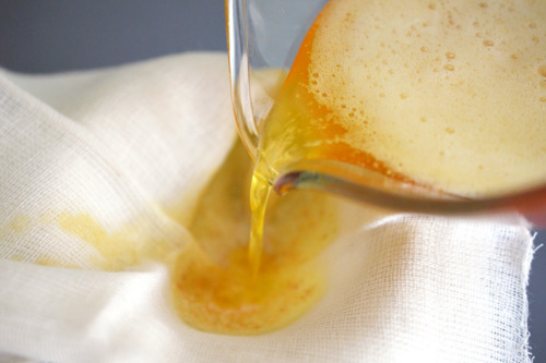 Straining the heated butter through a cheese cloth to make ghee.