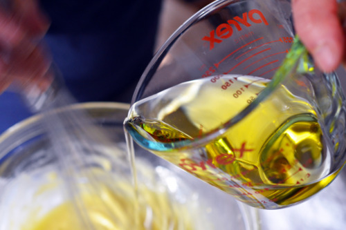 Pouring oil into a bowl with a whisk moving inside.