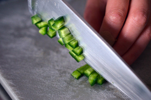 Someone chopping up jalapeño into small pieces.