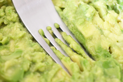 Mashing avocado with a fork for tuna and avocado wraps.