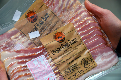 Someone holding Whole30-approved bacon packages.