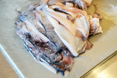 A pile of sliced raw squid prepared to be grilled.