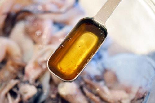 Measured oil that will be added to a bowl of raw squid for grilled calamari.