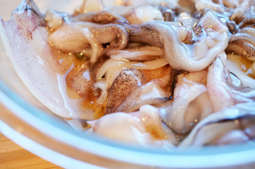 Raw squid with oil in a bowl for grilled calamari.