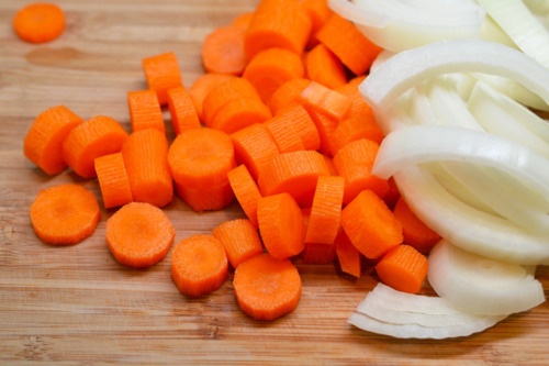 Chopped carrots and onions on a cutting board.