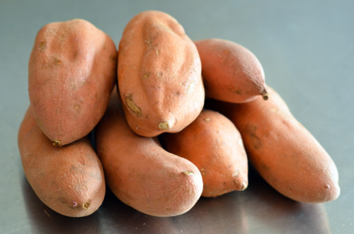 A pile of sweet potatoes on a counter.