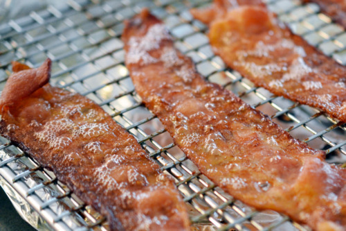 Cooked bacon pieces on a wire rack.