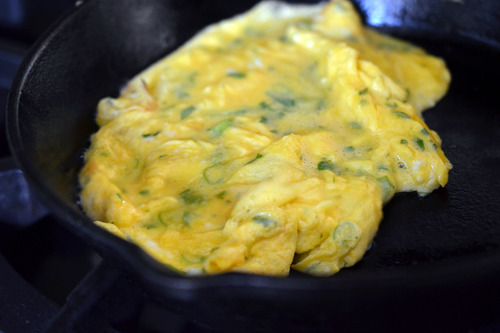 A closeup of the eggs cooking in a cast iron skillet.