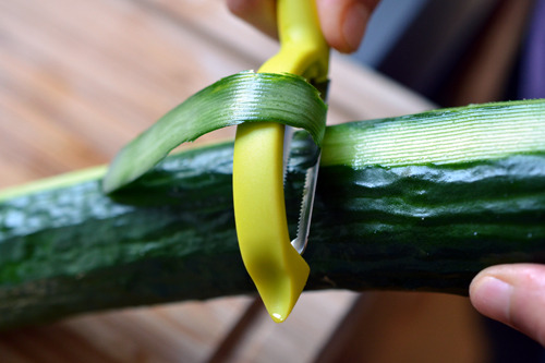 Someone peeling a cucumber skin.