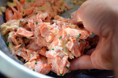 Someone mixing the salmon in a bowl for the spicy cucumber salmon bites.