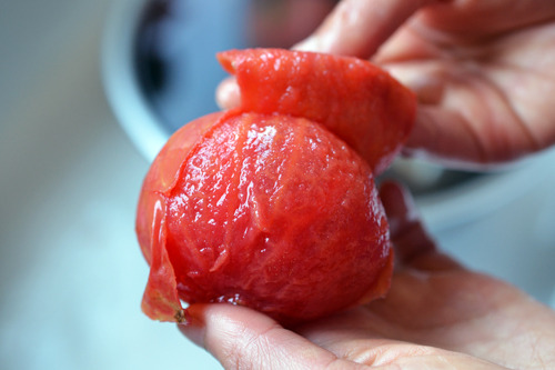 Someone peeling a tomato skin.