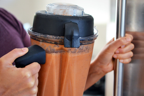 Someone putting the blender with watermelon and tomato gazpacho into a fridge to cool.