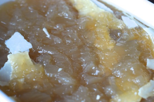 The fat cap top of a cooled beef bone broth recipe that is in a container.
