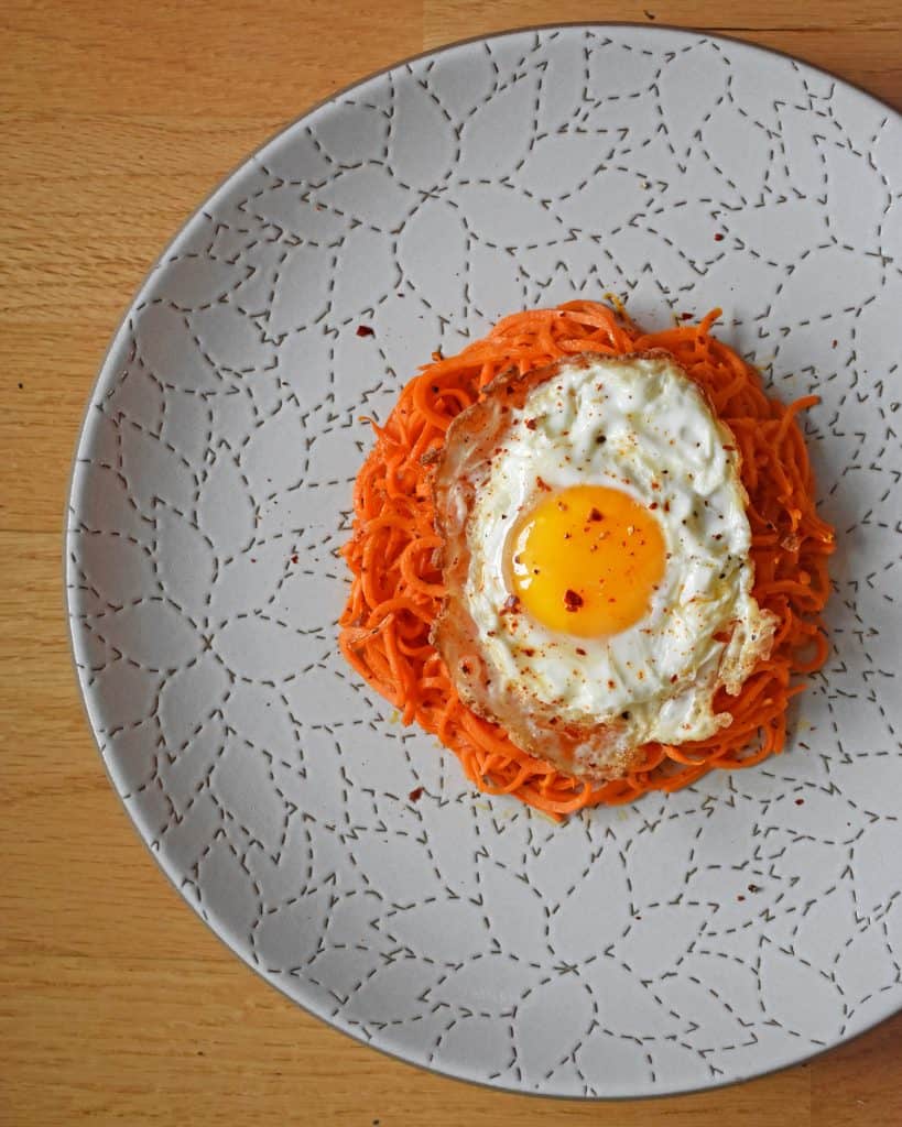 An overhead shot of Sweet Potato Hash with Fried Eggs on a white plate.